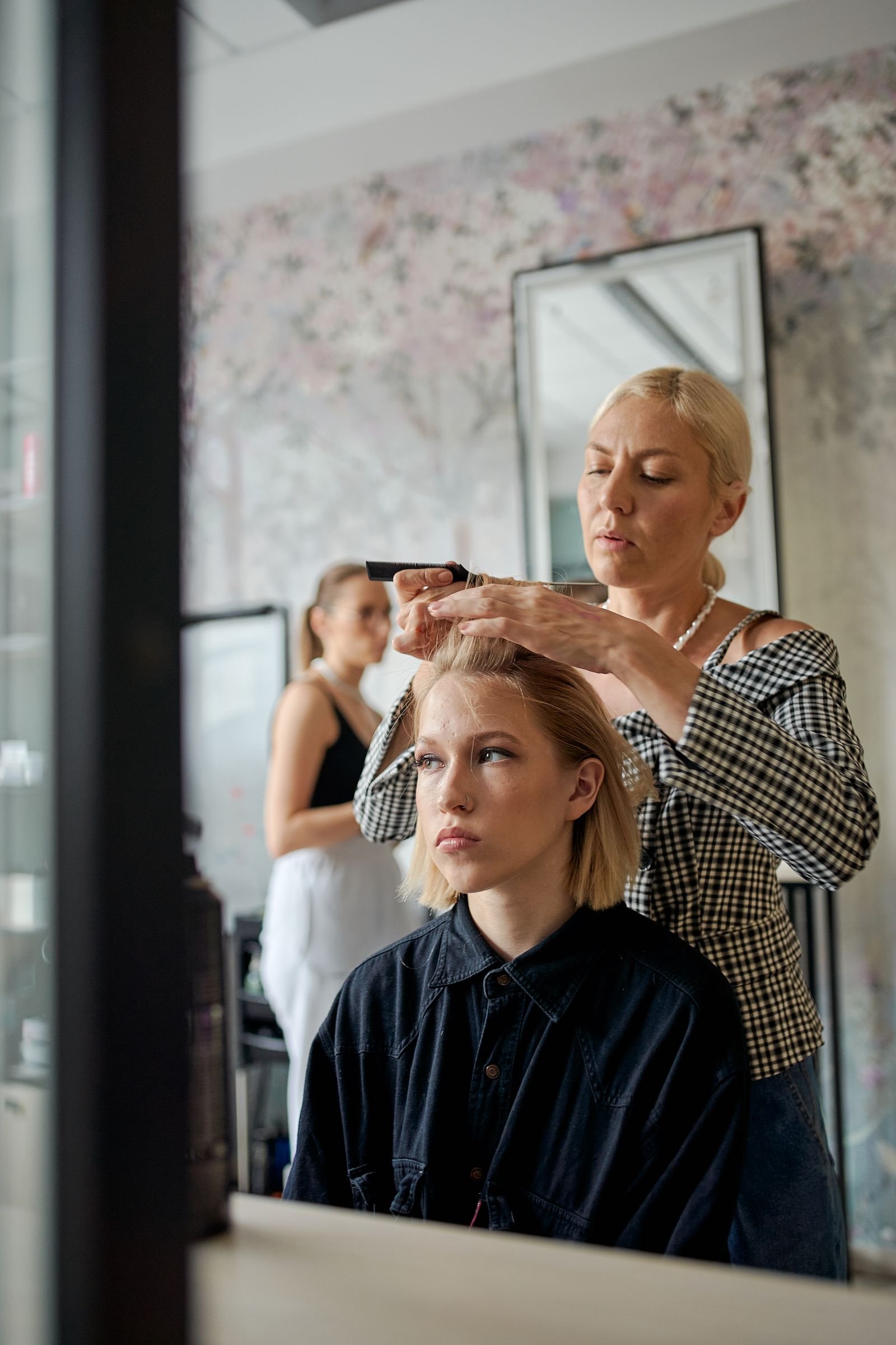 Profissional penteando o cabelo de uma cliente no salão
