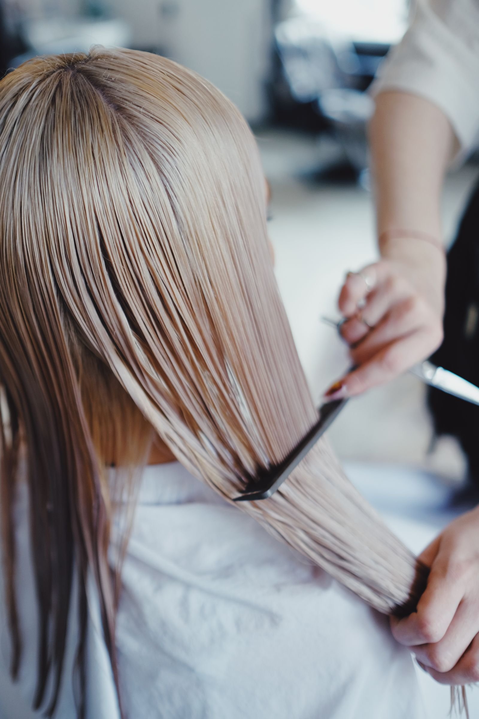 Corte sendo feito em cabelo longo, com atenção aos detalhes